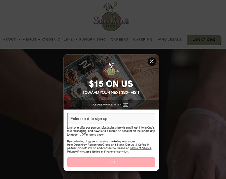 Popup on a website offering a $15 discount on a $30 purchase at Stan's Donuts & Coffee in exchange for email sign-up. The background shows a tray of assorted donuts.