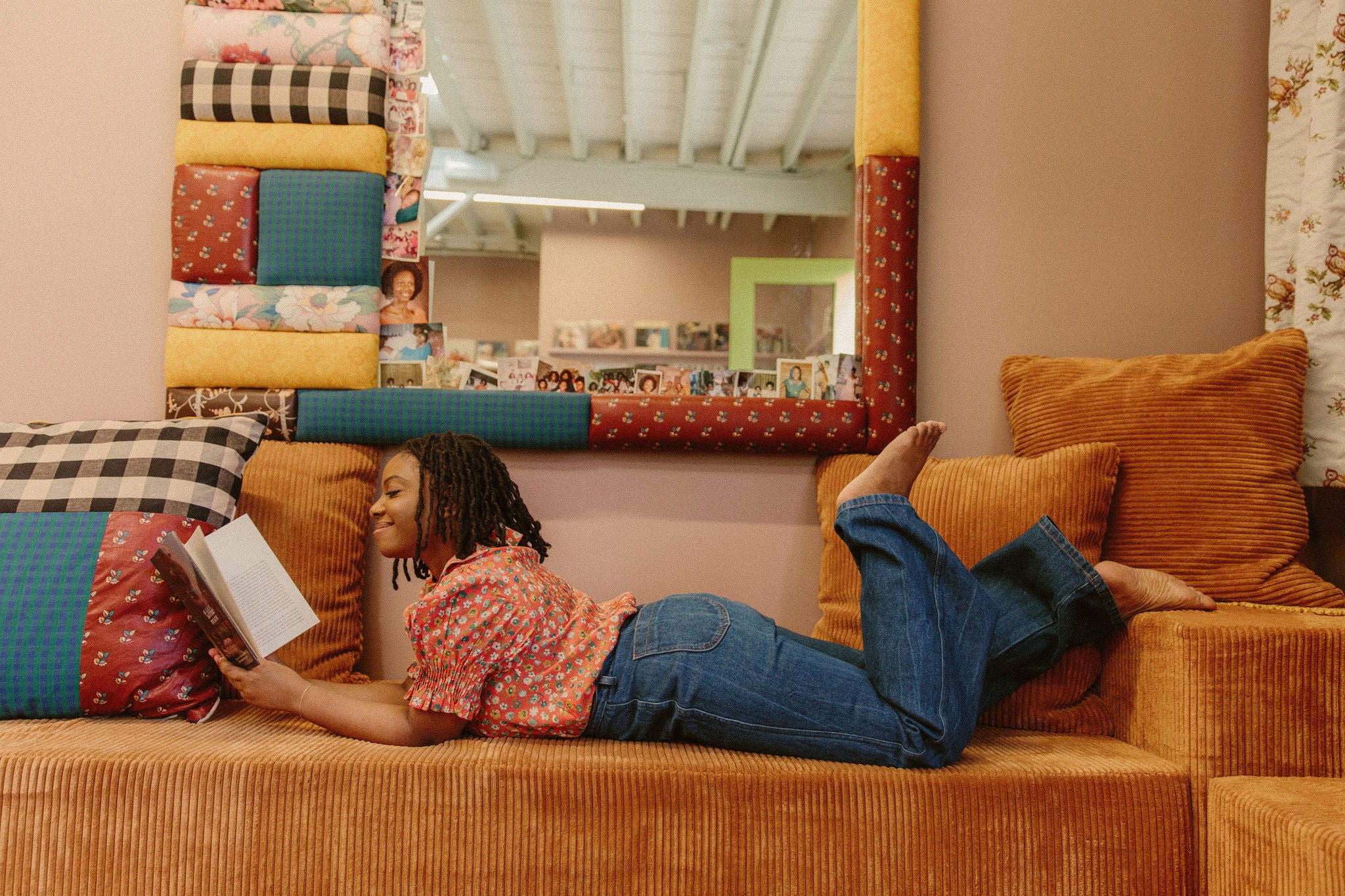 Jazzi McGilbert laying on a couch at Reparations Club and reading a book