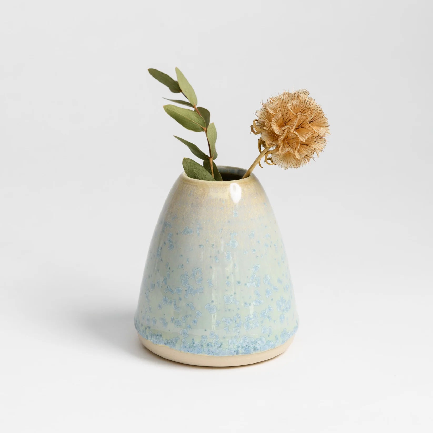 A small ceramic vase holding a single flower is a craft you can make and sell