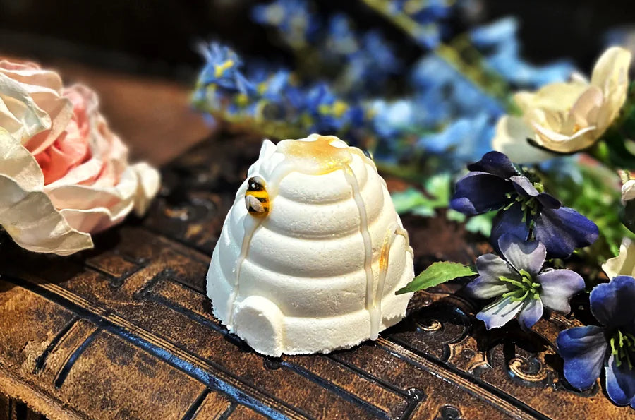 A behive shaped bath fizzy is arranged with dried flowers on a wooden surface