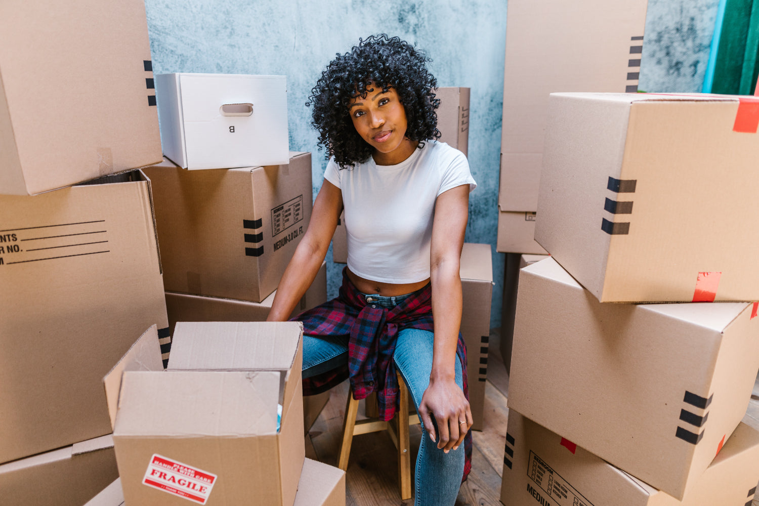 Person sits among a pile of cardboard shipping boxes