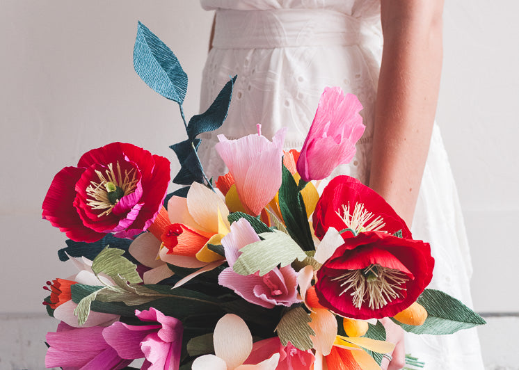 A woman in a wedding dress holda q bouquet of paper flowers, which are crafts you can make and sell