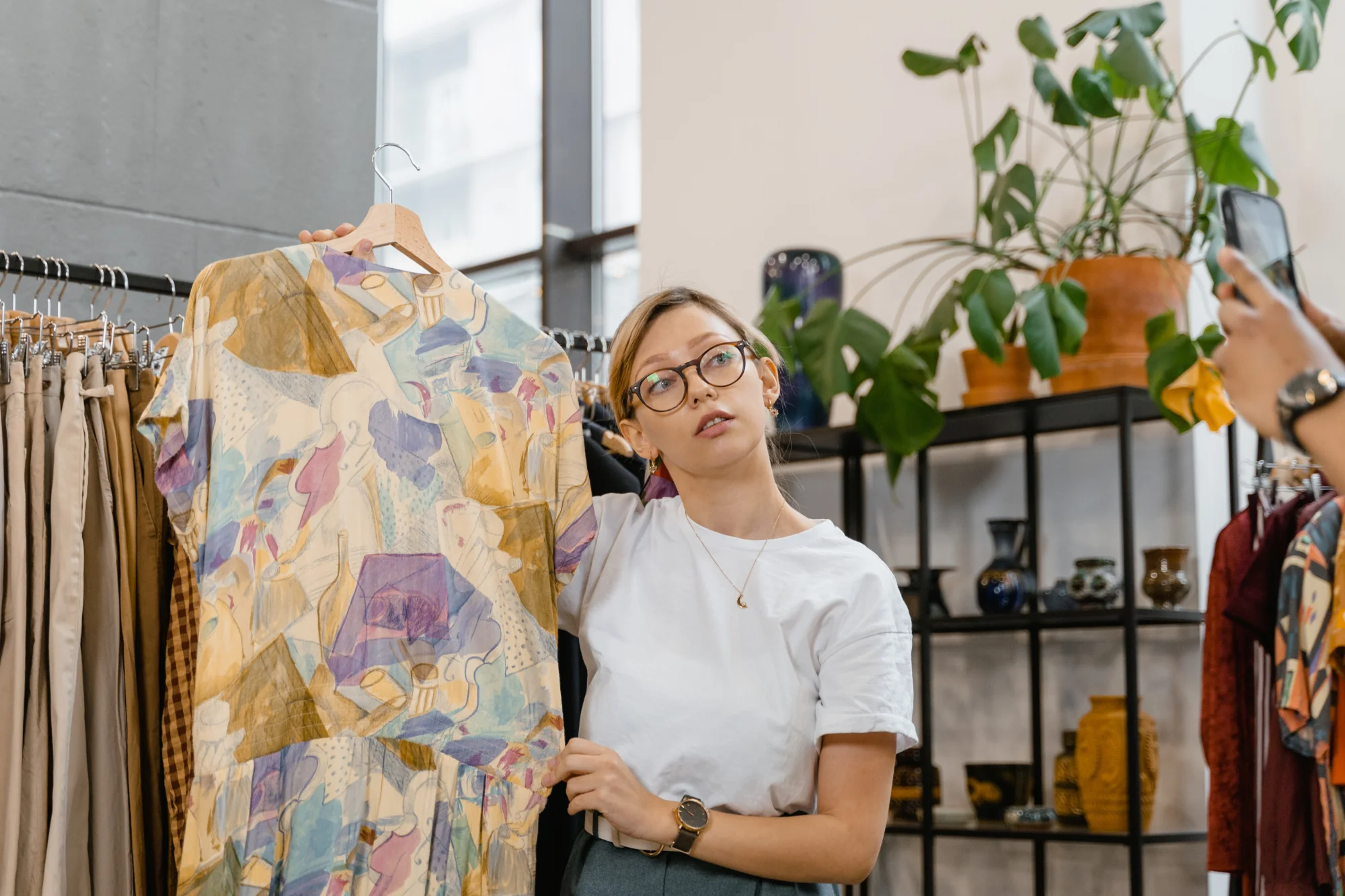 A woman holds up a vintage shirt in a retail store