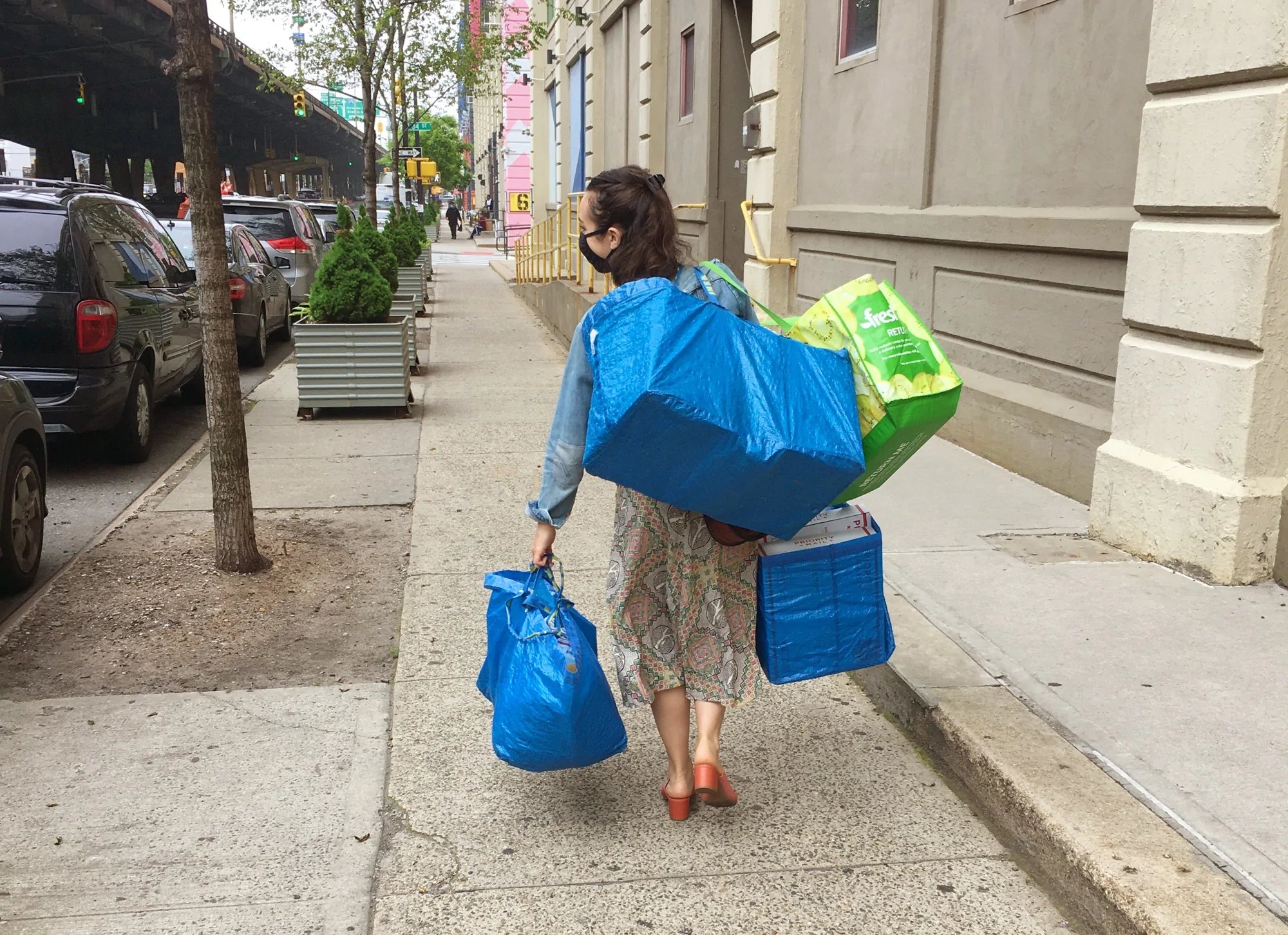 A business owner walks along the street carrying IKEA bags full of vintage clothing