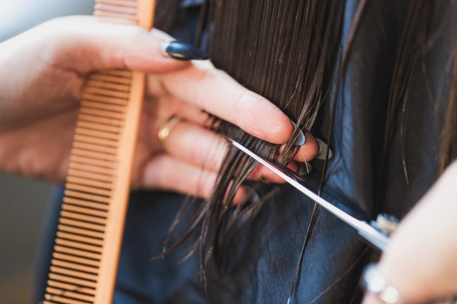 A woman cuts hair with a comb and scissors