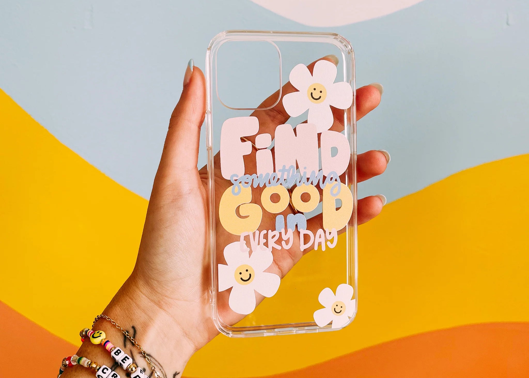 A hand holds a transparent plastic phone case emblazoned with illustrated designs
