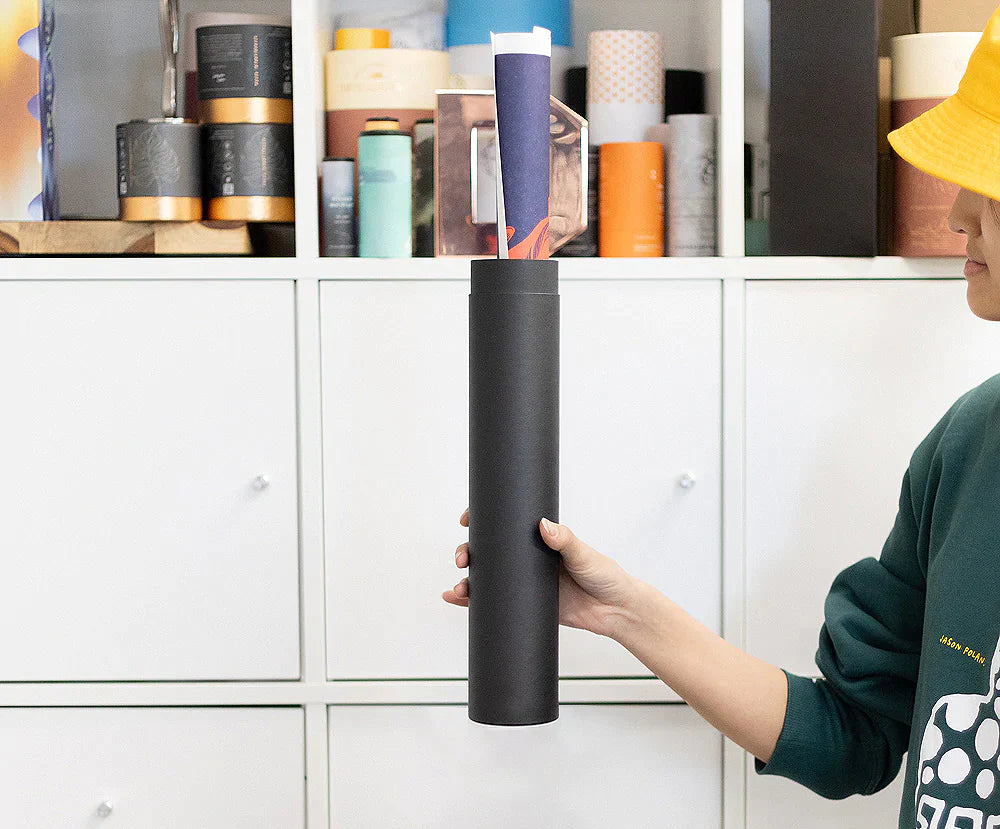 A person holds a cardboard tube used for shipping art