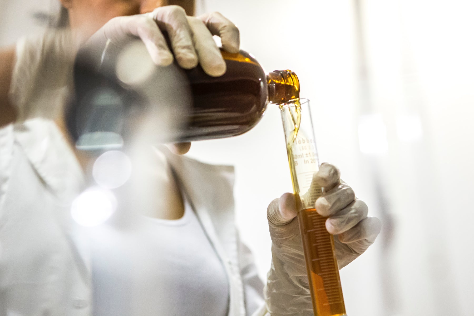 A person pours a liquid into a vial in a lab setting