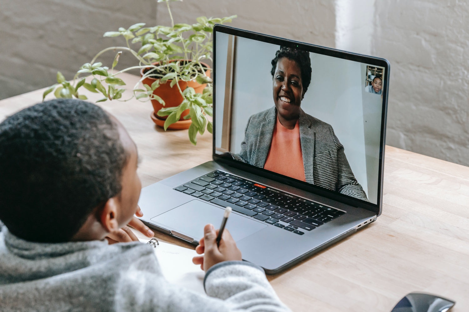 A child speaks to a woman over a video chat on a laptop