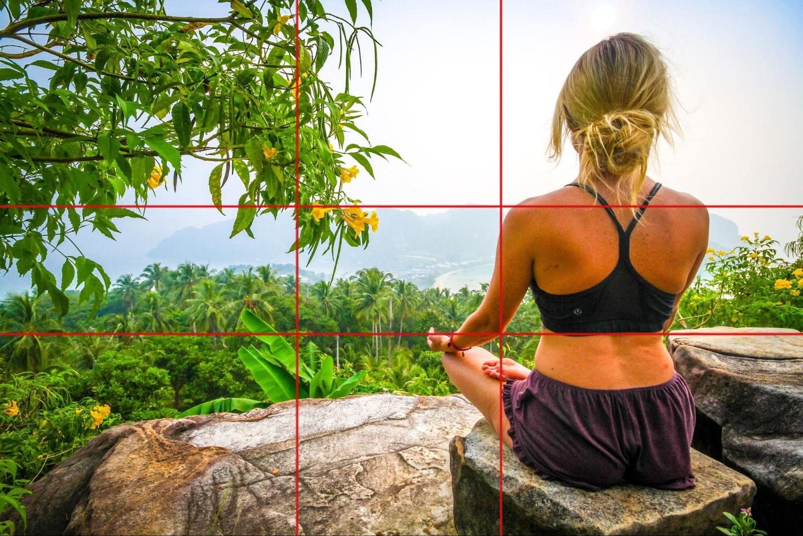 picture of woman sitting cross legged on a rock looking , with two lines horizontal and vertical showing the golden ratio