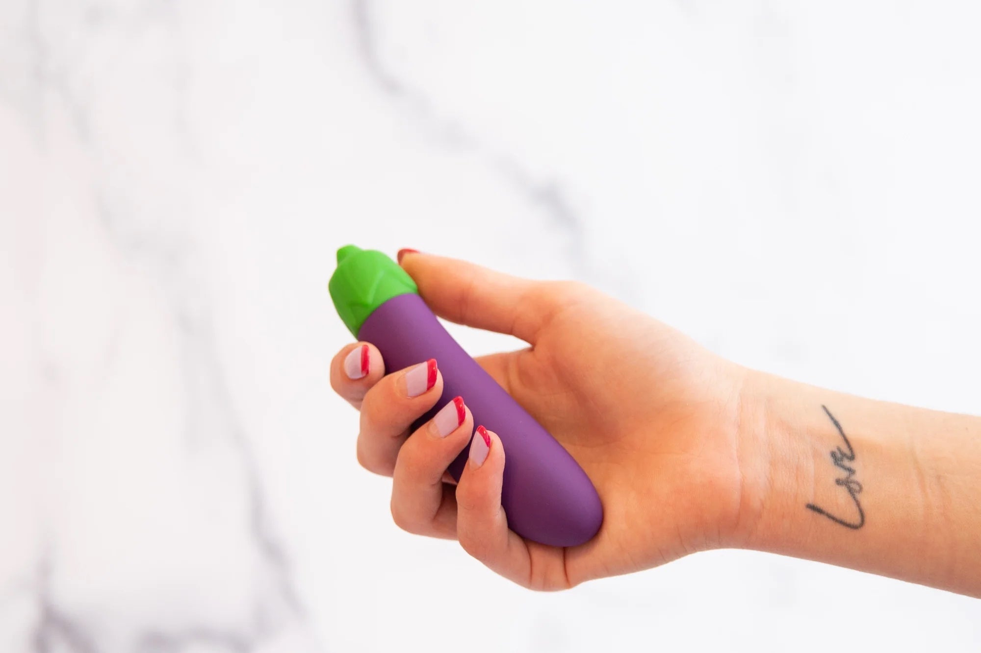 A person holds a small eggplant vibrator