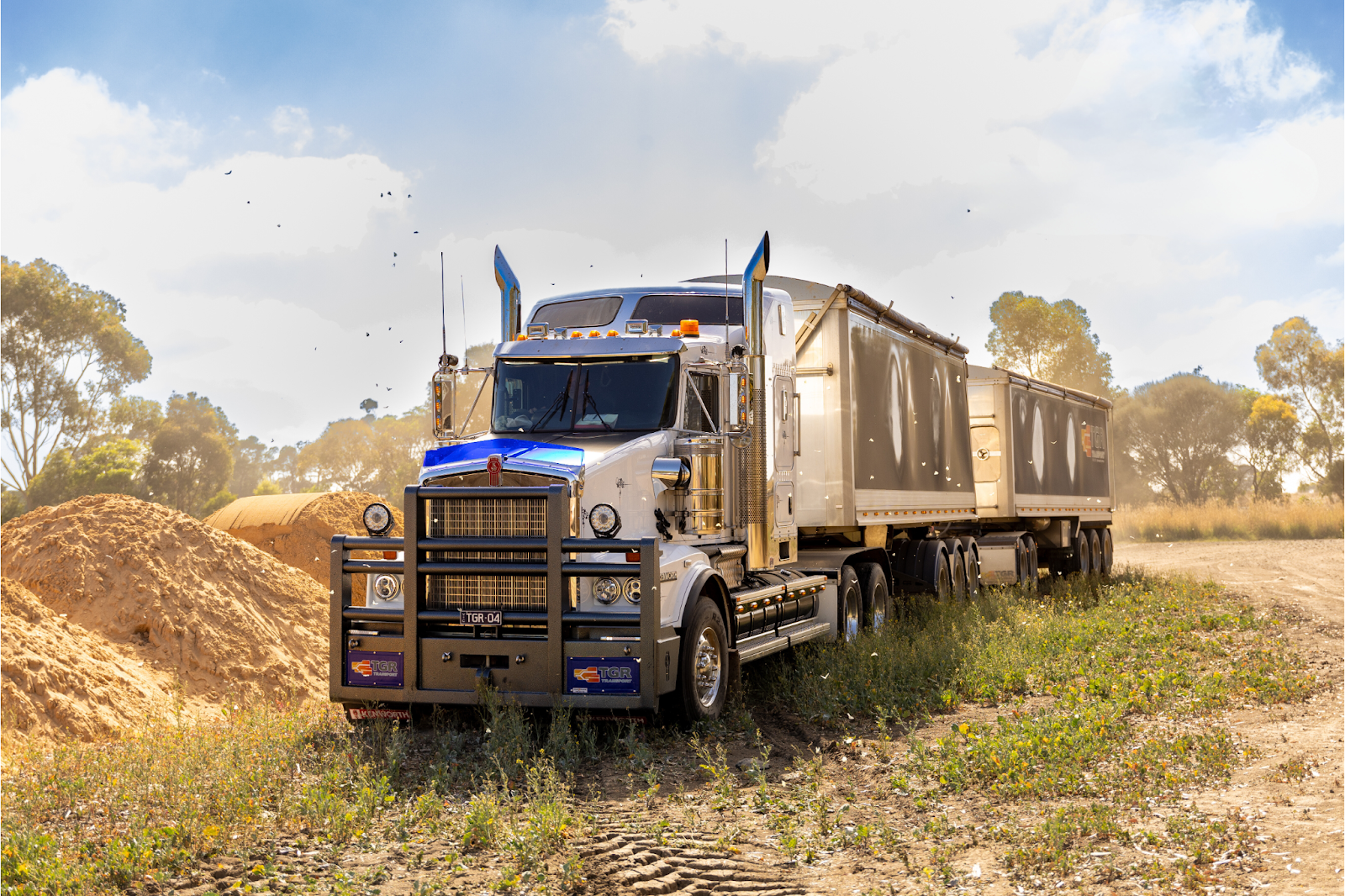 Big rig truck parked in a field with a blue sky