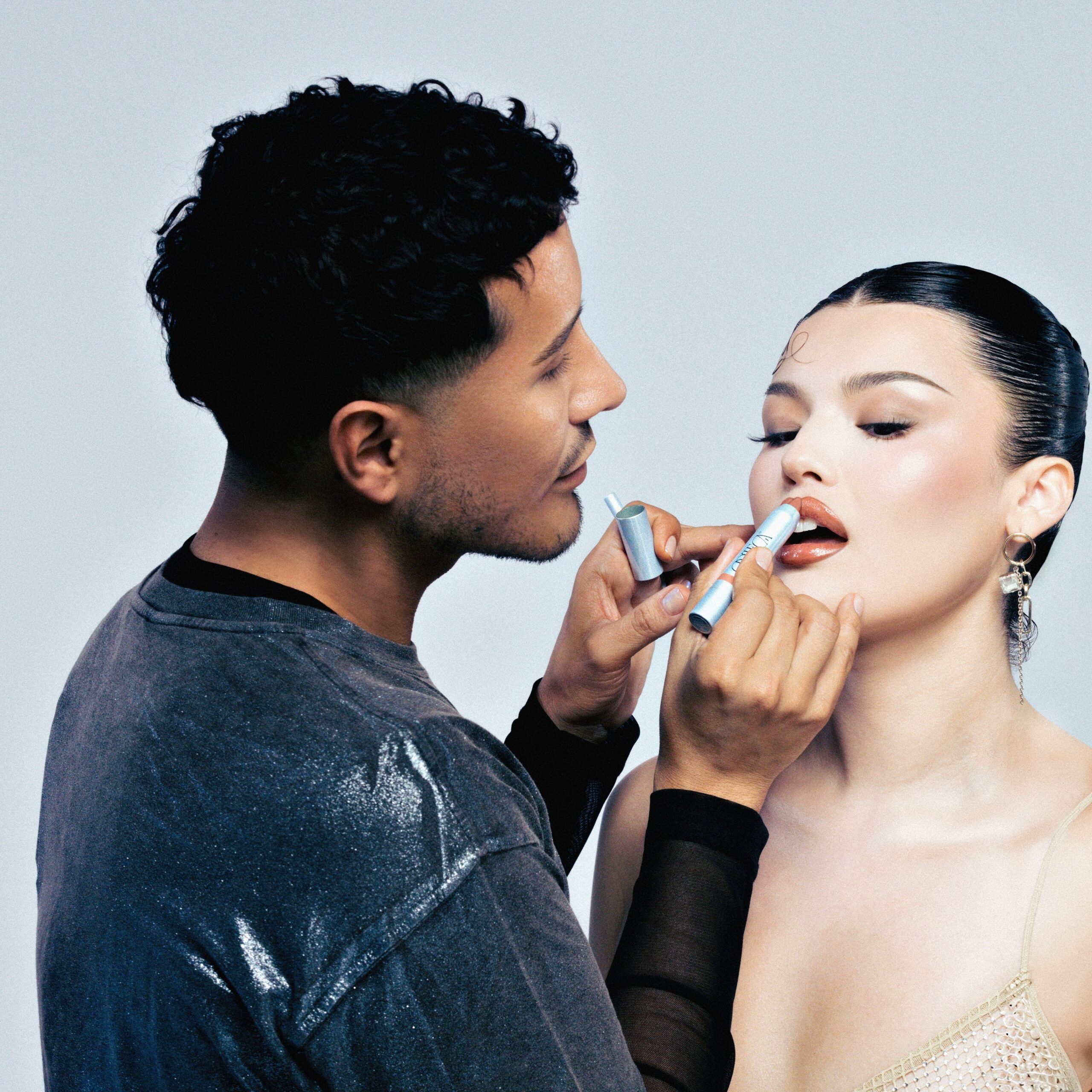 Etienne applies an ORTEGA lip product onto a model.