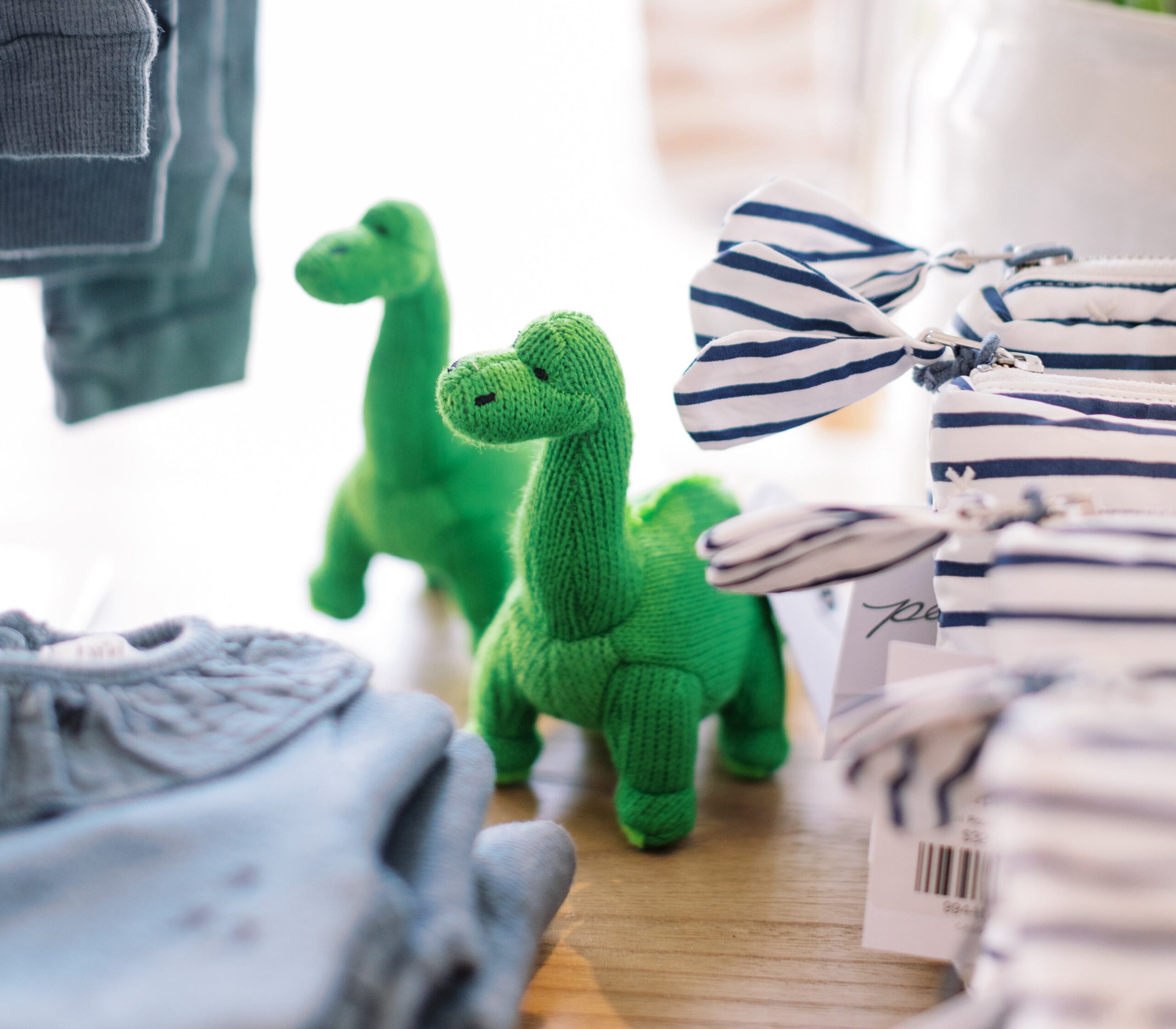 two stuffed dinosaurs stand in between stacks of clothing at the francis henri store.