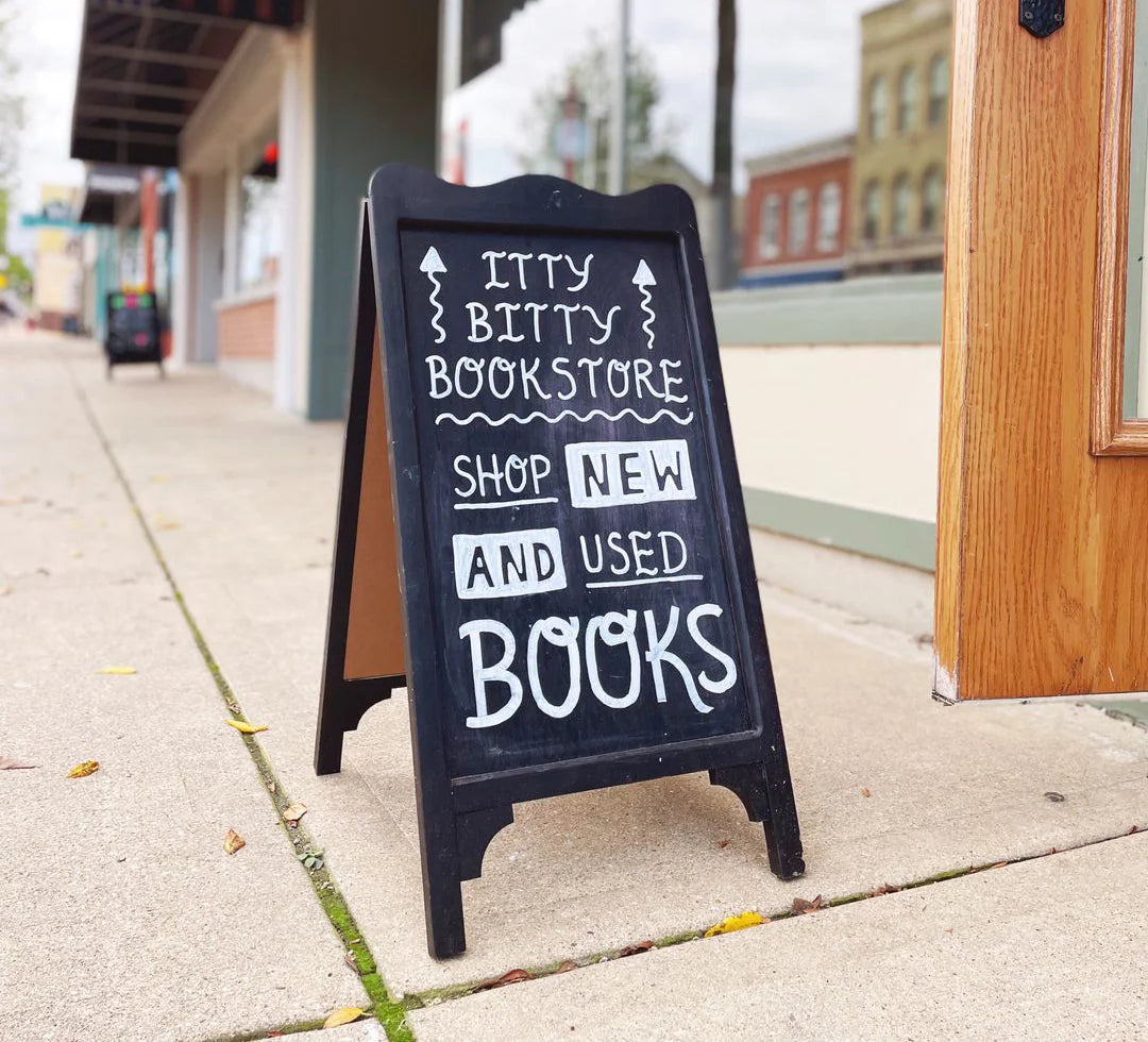 Sandwich board sign on a sidewalk in front of a bookstore