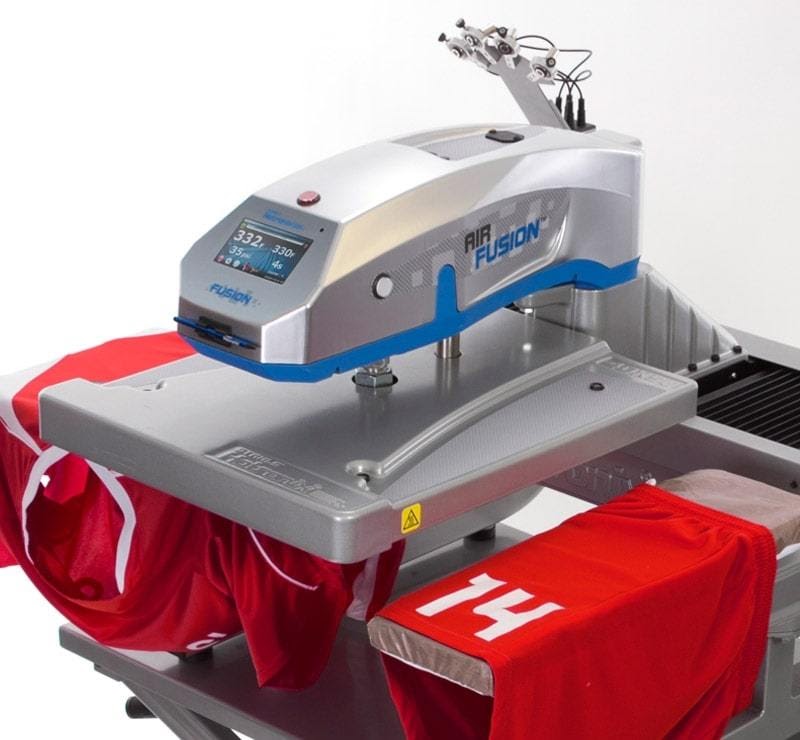 Gray heat transfer machine being used to print the number 14 on a red soccer jersey.