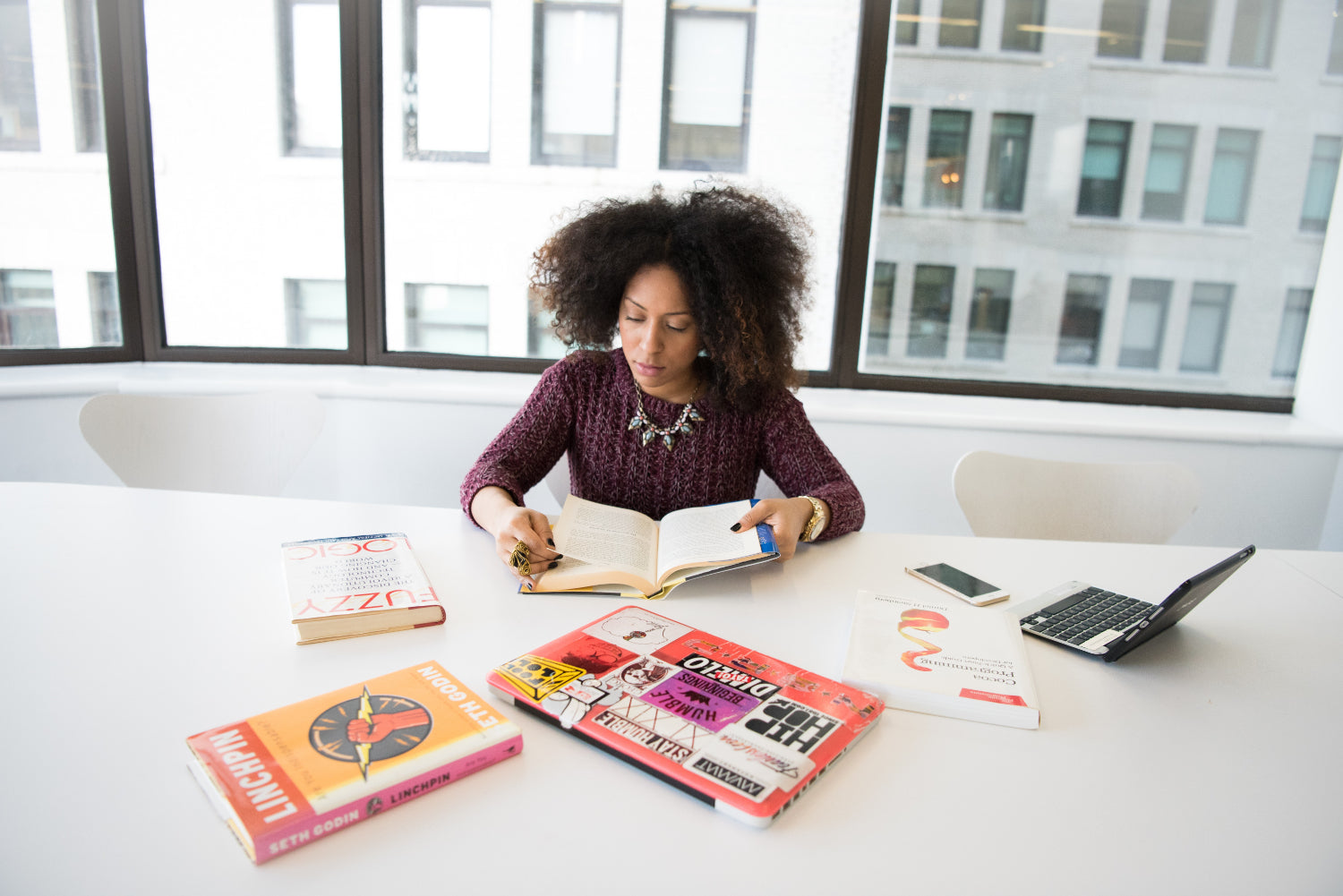 Woman sits at a boardroom table looking through some books