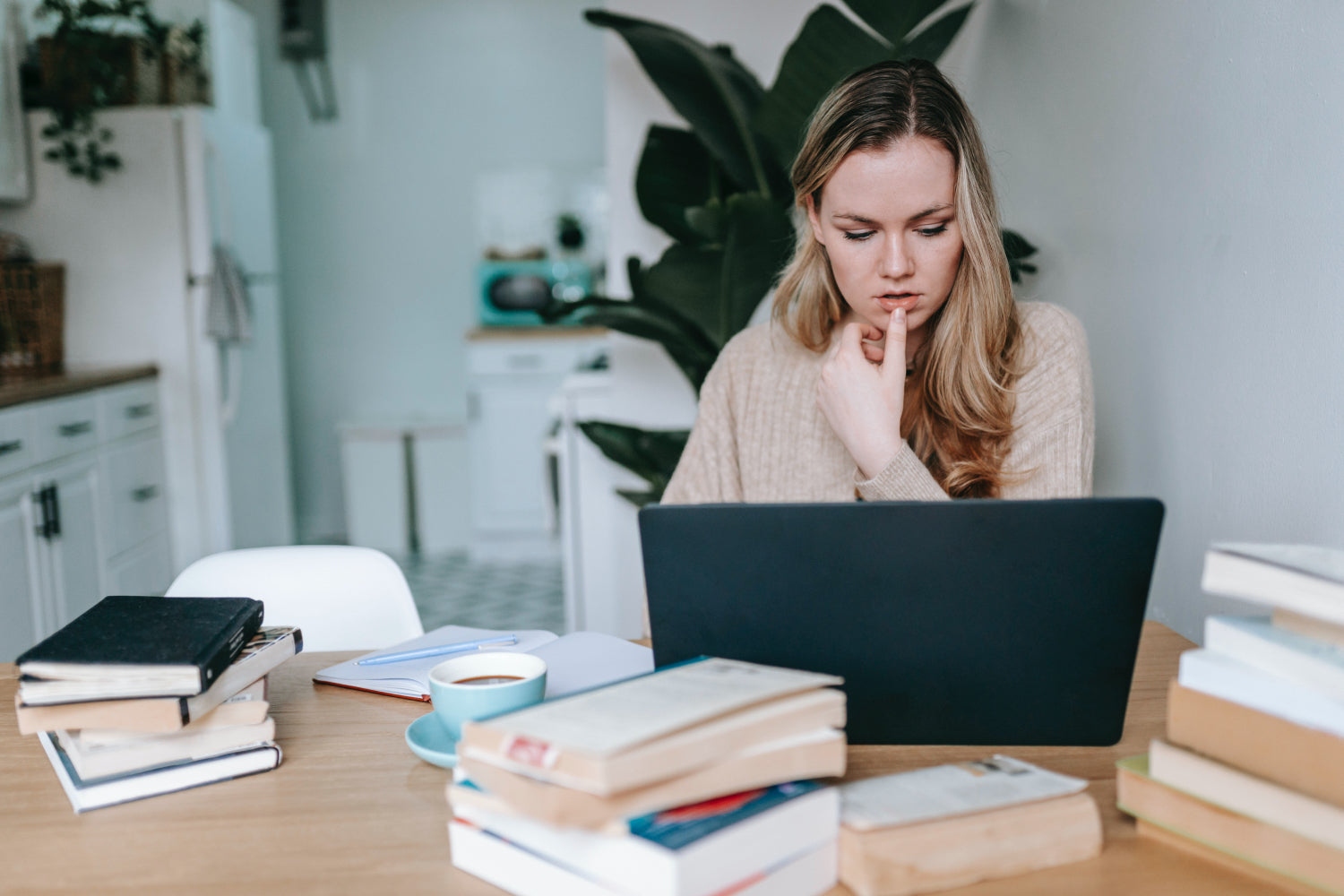 Woman works at a laptop surrounded by books