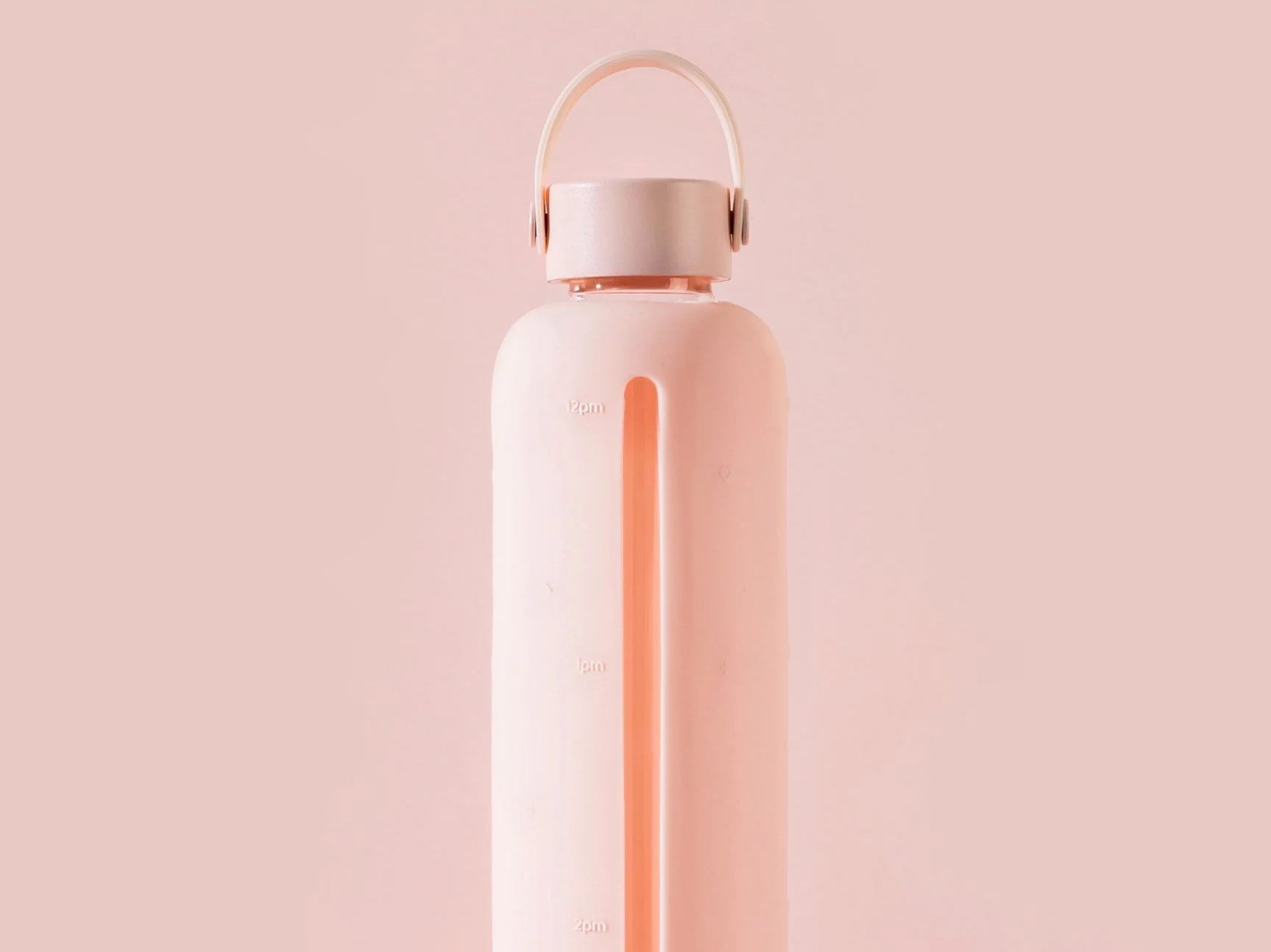 The top half of a Healthish peach rubber covered glass water bottle against a matching background.