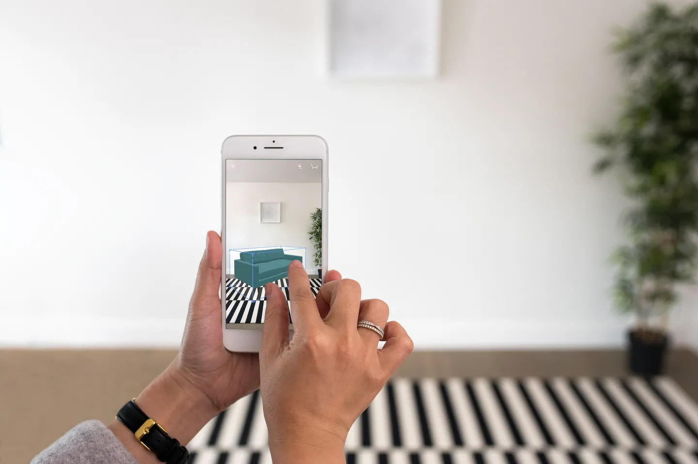 A customer using their iPhone to see how a teal sofa would look in their living room.