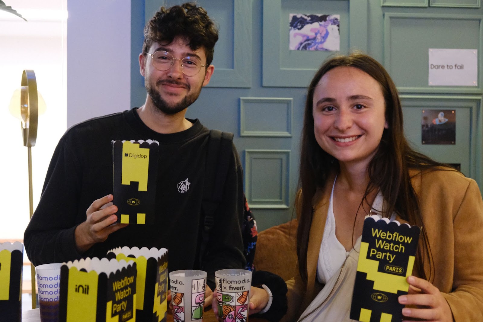 Two people smiling and holding popcorn boxes at a Webflow Conf watch party in Paris in 2023.