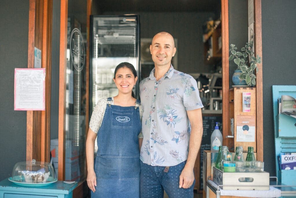 Rejoice and Adam Thomson standing in front of their cafe smiling