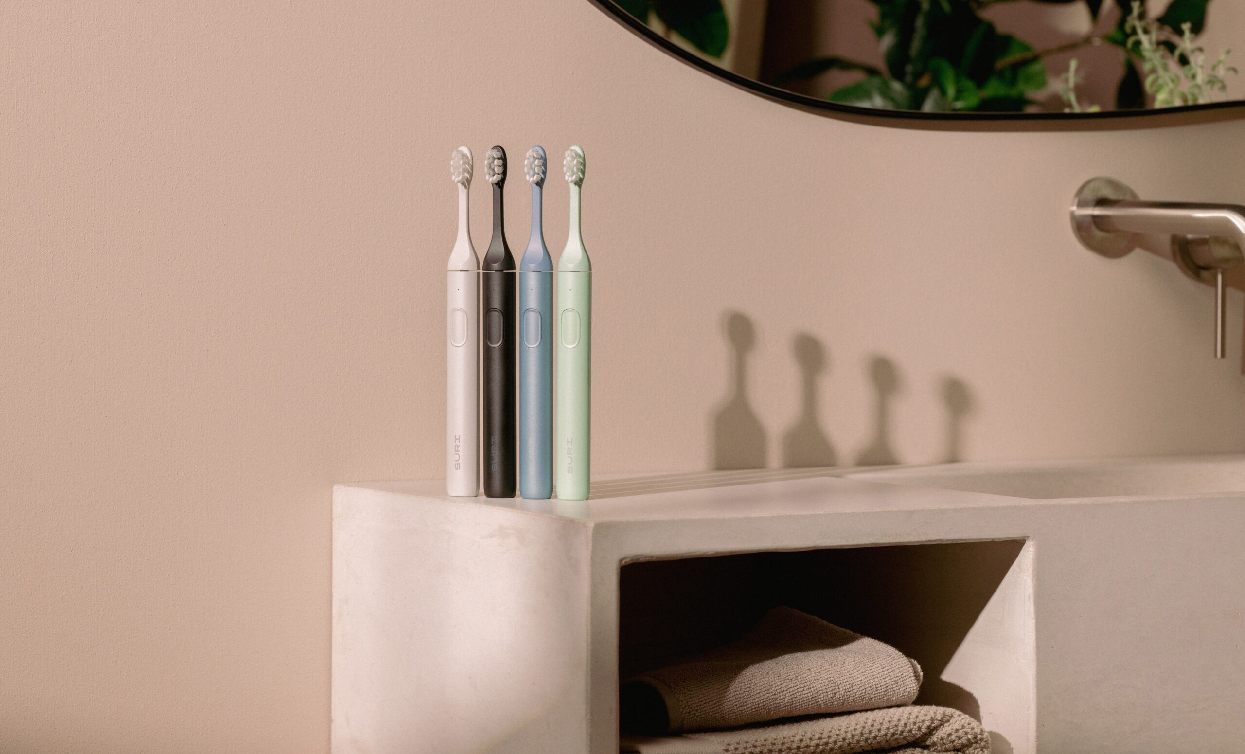 the suri electric toothbrush in four colors sitting on a countertop.