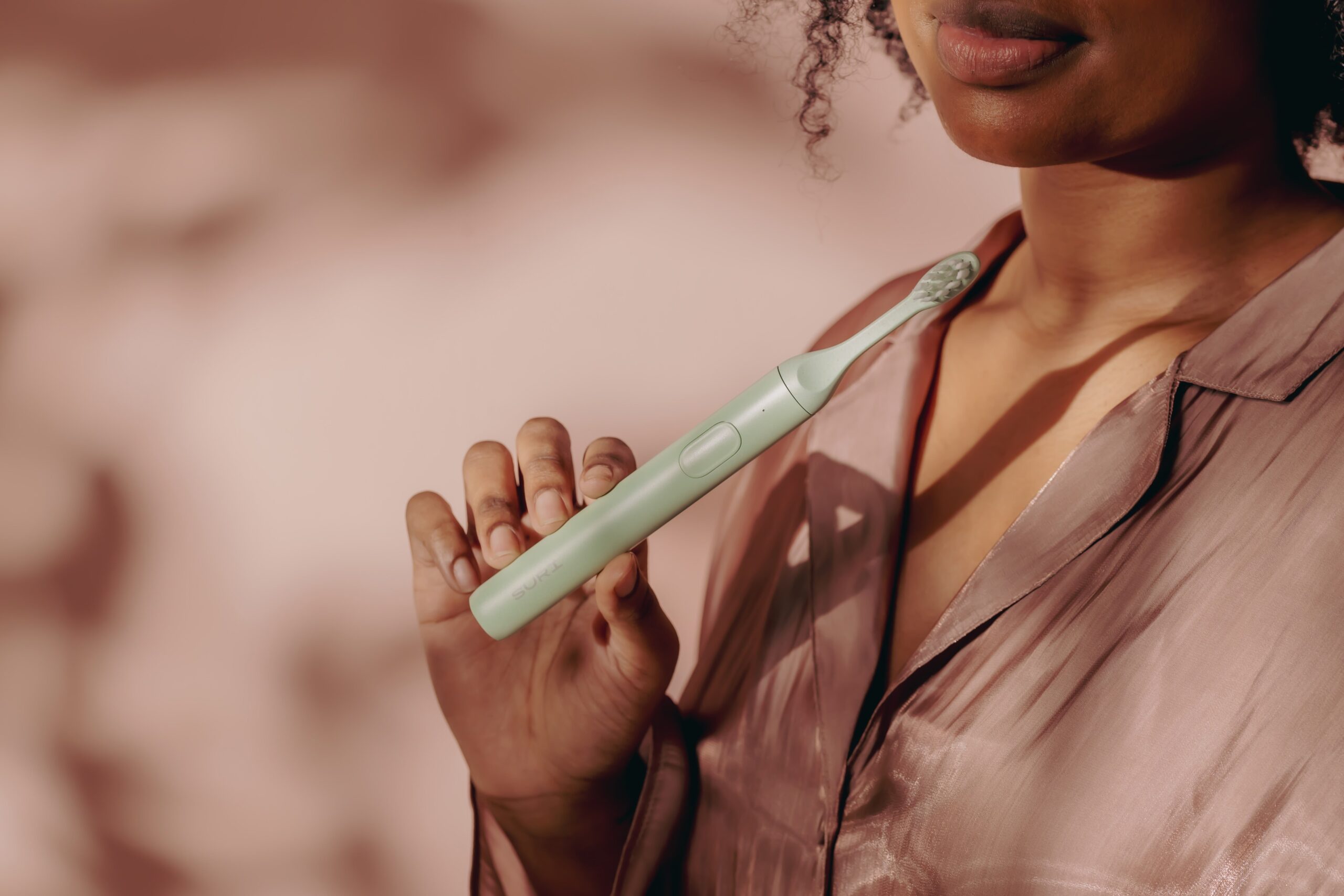 suri’s electric toothbrush in color winter fern being held in the hands of a model.