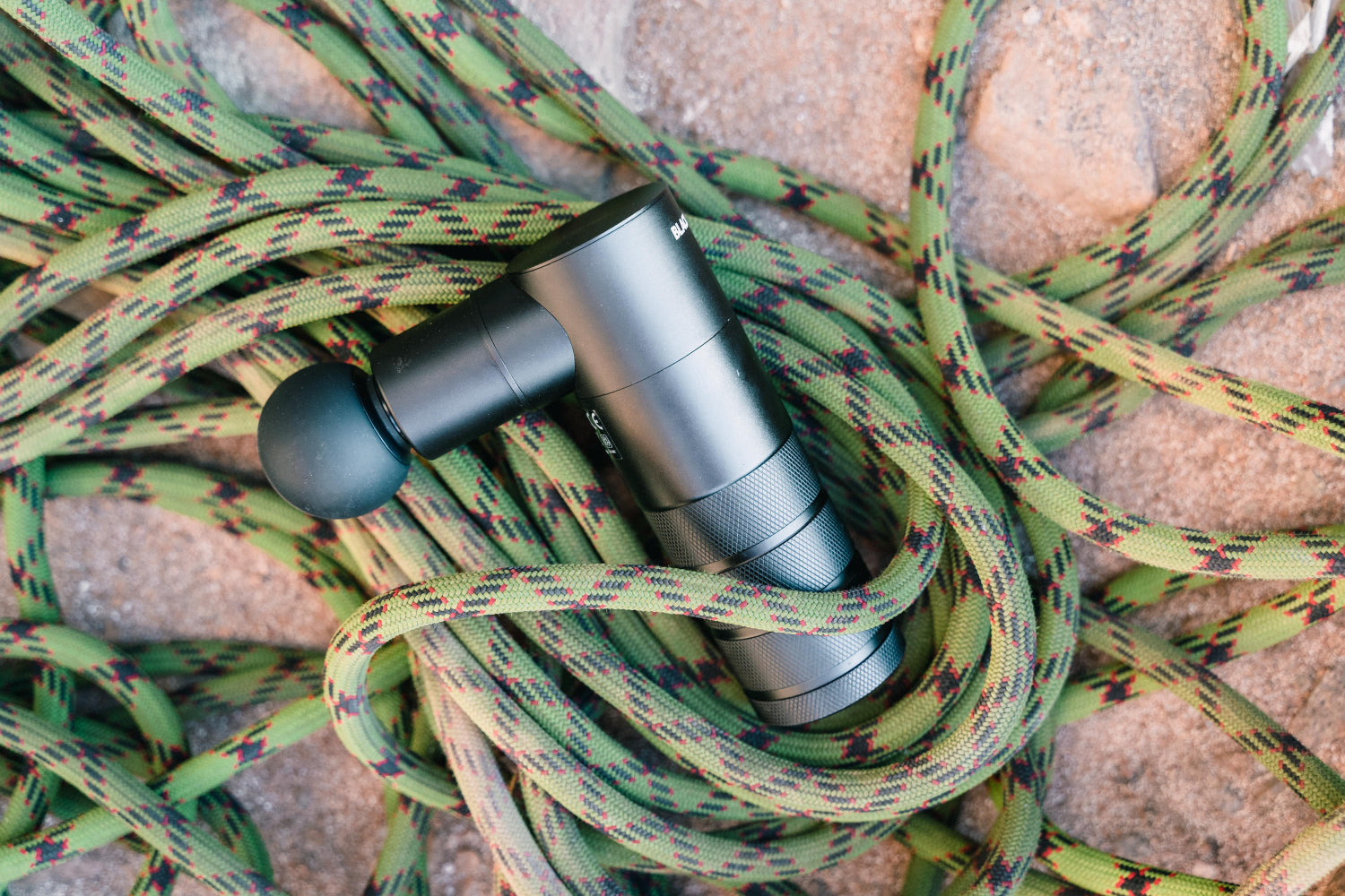 A massage gun sits among coils of rope