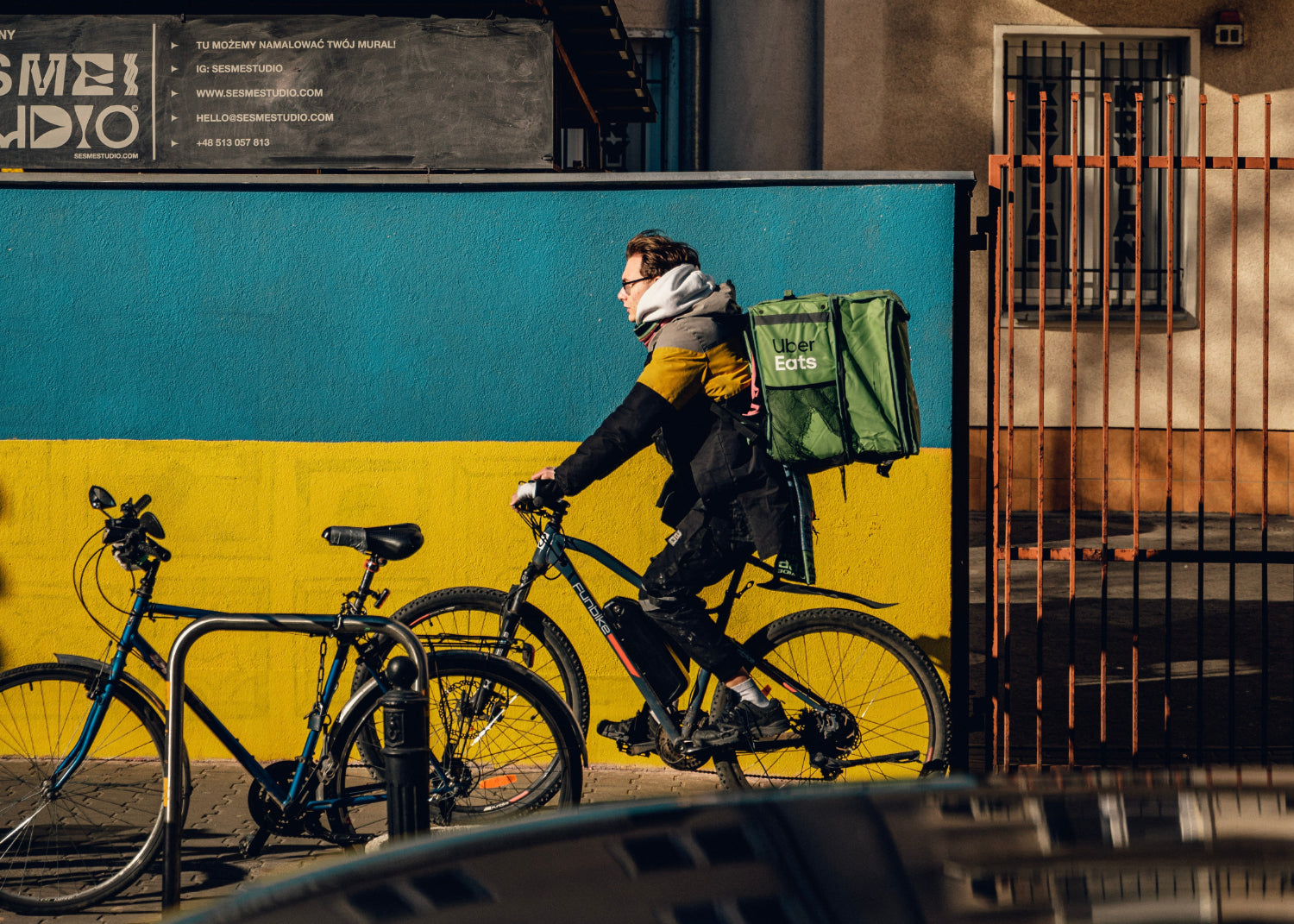 Uber Eats delivery person riding a bike past a colorful wall.