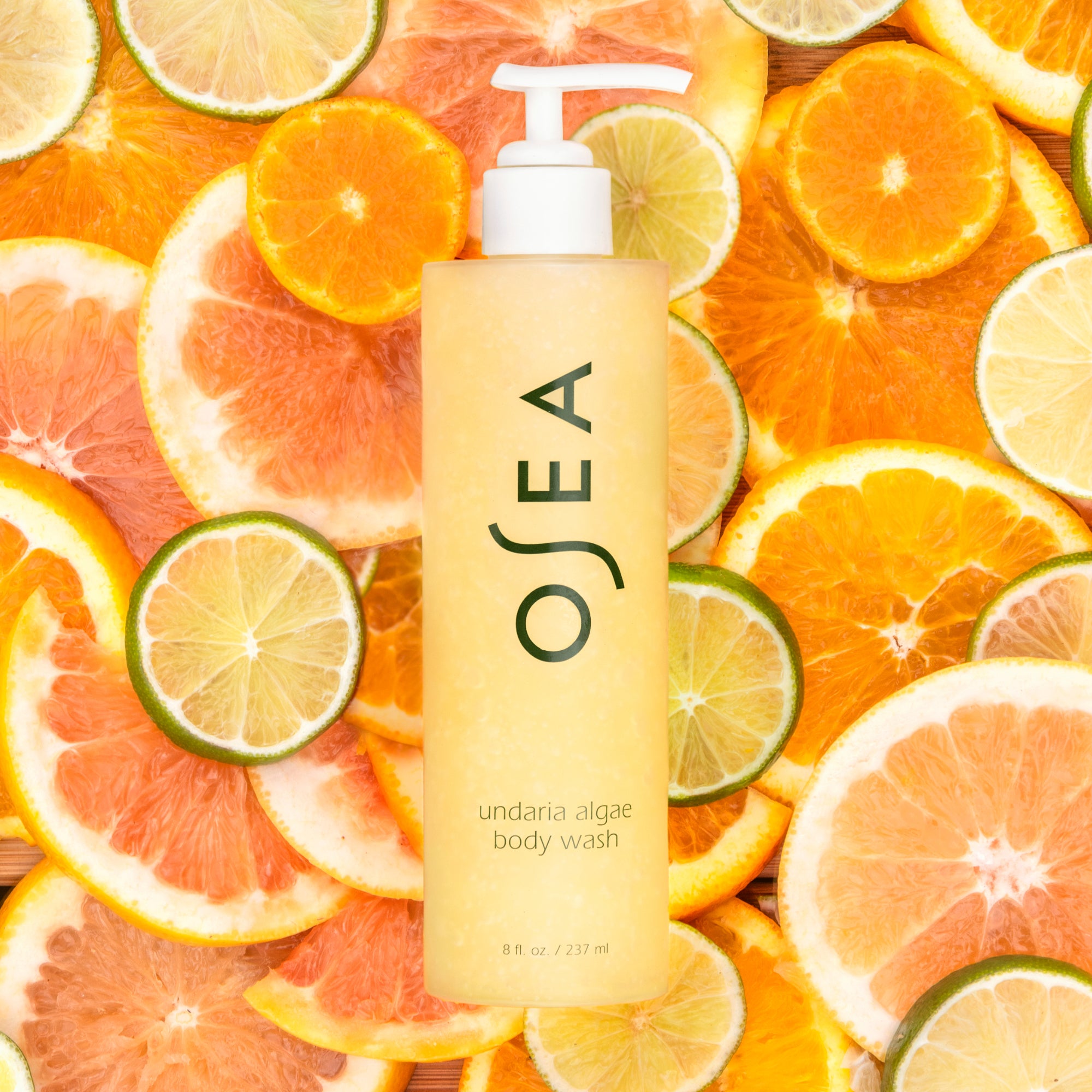 OSEA’s undaria algae body wash pictured in front of a bed of sliced oranges and limes.