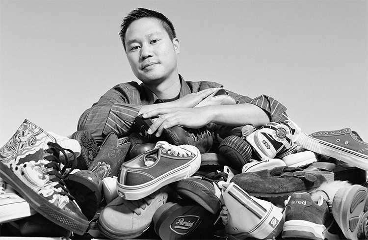 A man leans on a large pile of assorted shoes while looking at the camera.