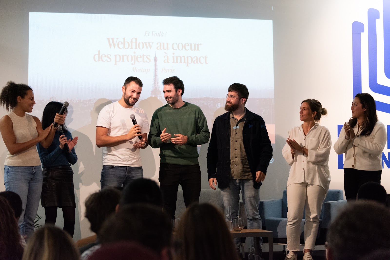 group of people on stage speaking at a webflow conf watch party in paris