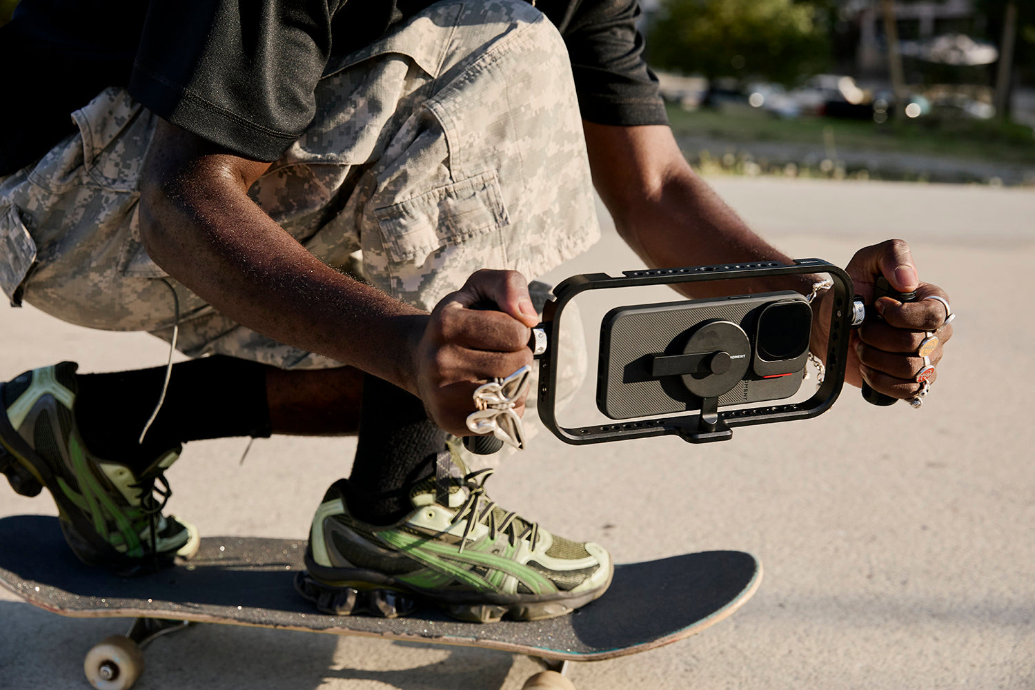 A photographer holding a phone camera on a gimbal while skateboarding