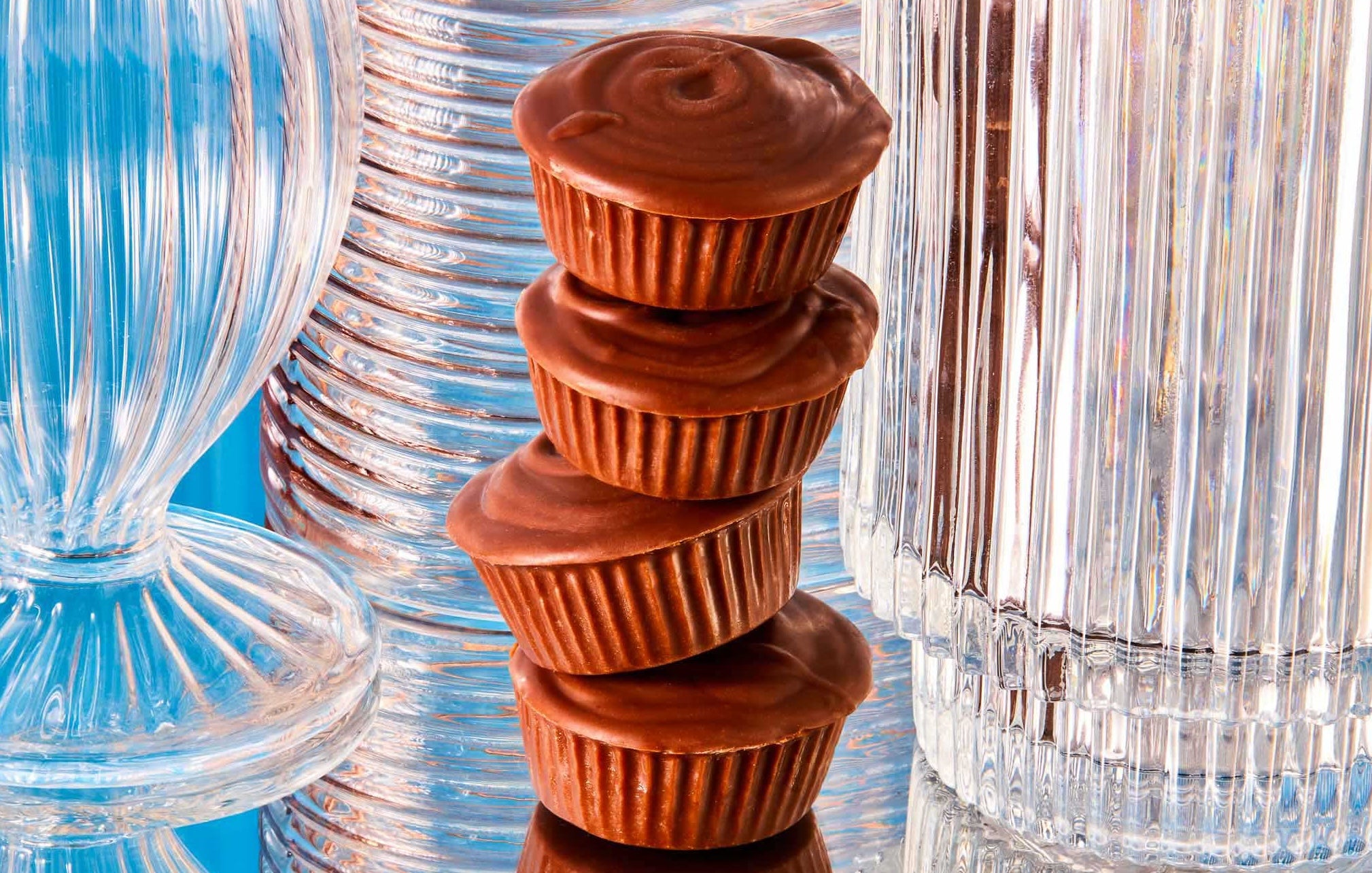 Compartés’ peanut butter cups stacked on top of one another with funky shaped glassware behind them.