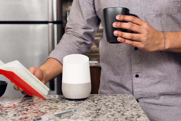 This man prepares for his day by reviewing his to-do list with coffee in hand, and smart home assistant by his side.