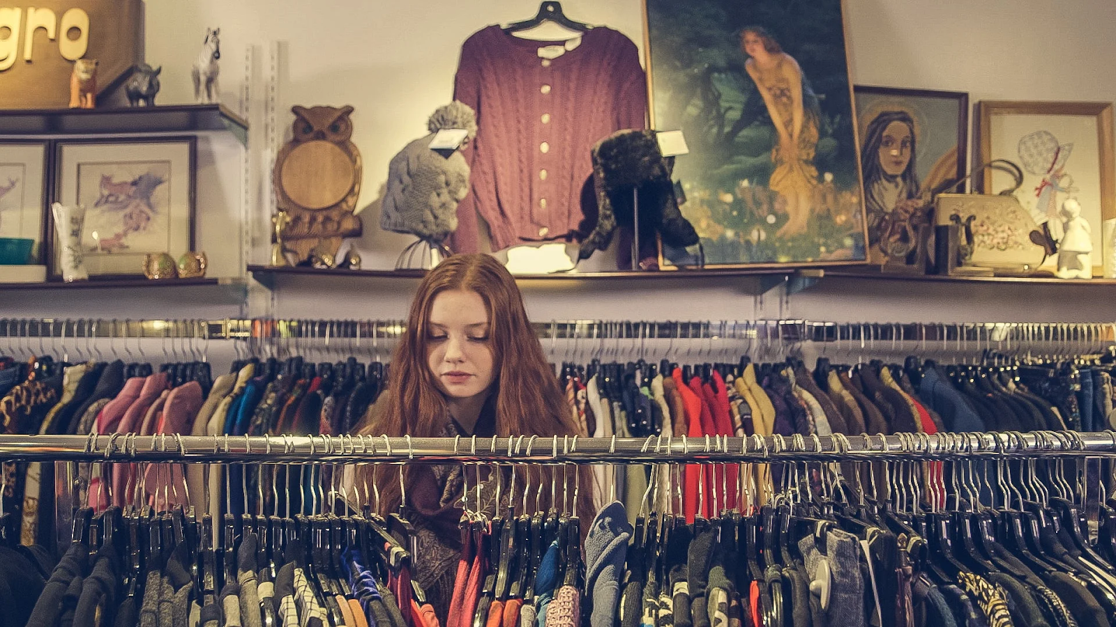 A person browses a clothing rack in a small boutique.