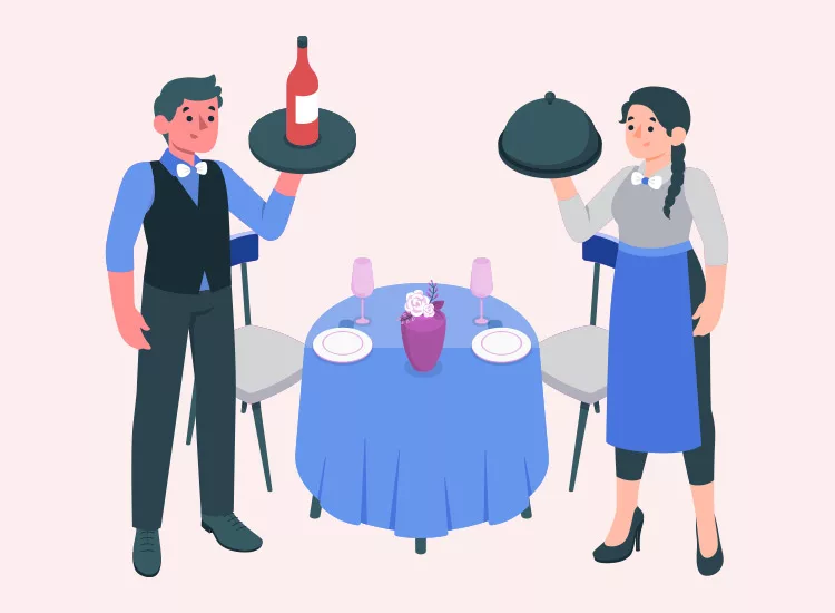 Two servers standing by a dining table with a blue cloth. The male server holds a bottle on a tray, and the female server holds a covered dish. The table has two chairs and glasses.