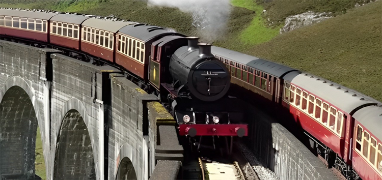 A steam train crosses a stone viaduct in a green landscape, with smoke billowing from its chimney.