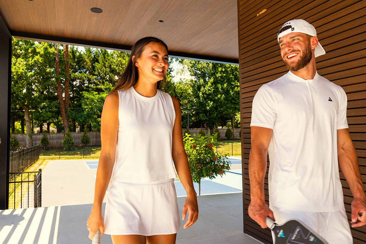 A woman and man walking in white Joola pickleball apparel