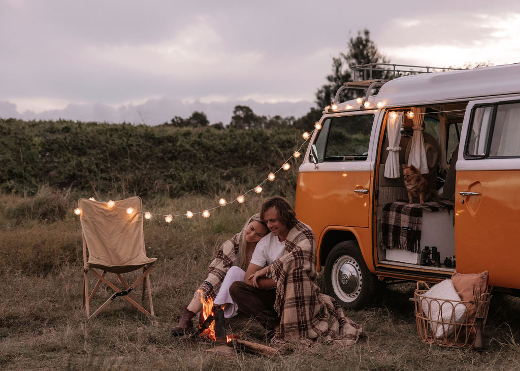 A couple underneath a blanket sitting next to their RV