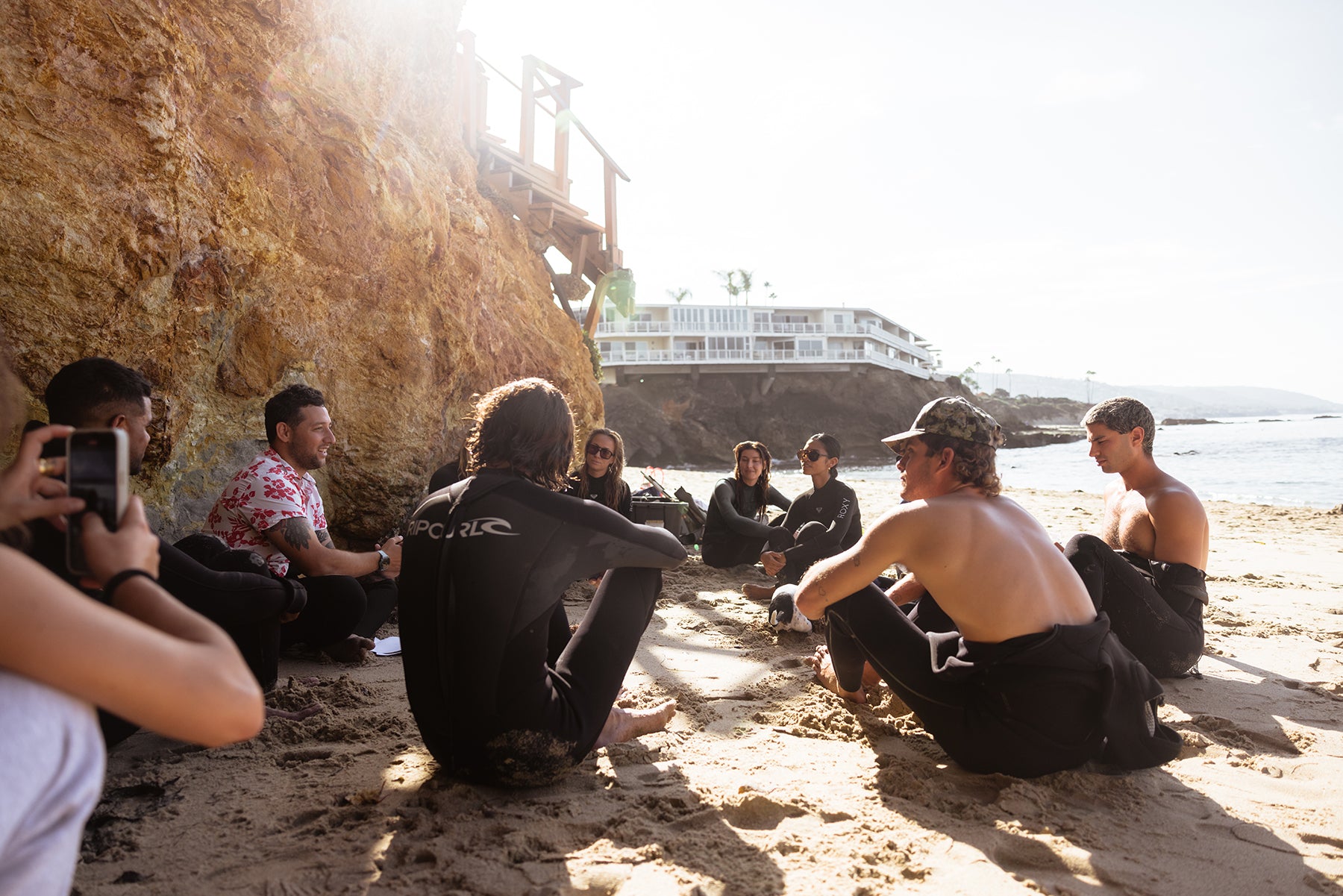 a group in wetsuits gathered by the beach