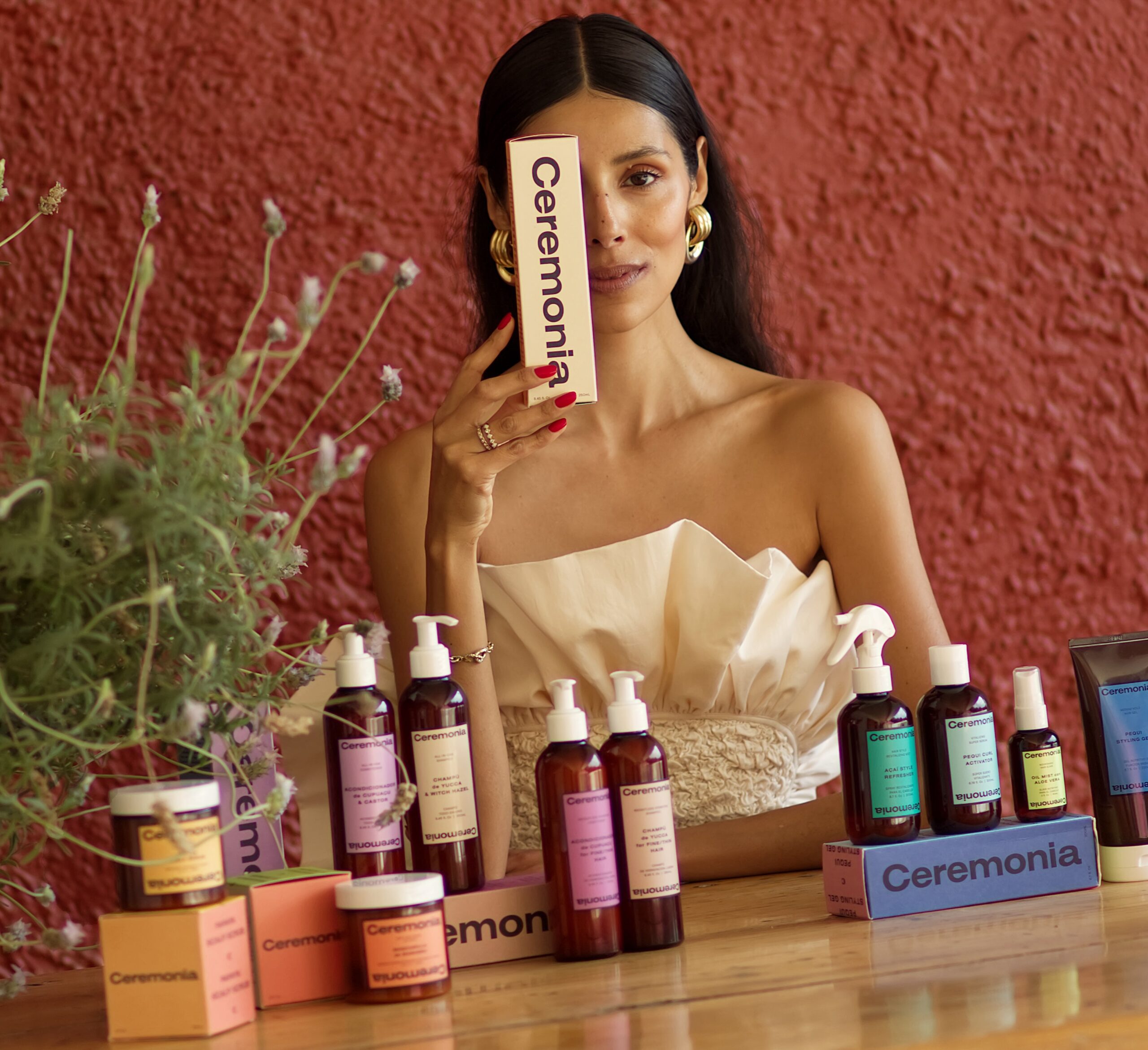 ceremonia products on display while the founder babba rivera holds a ceremonia box over her right eye.