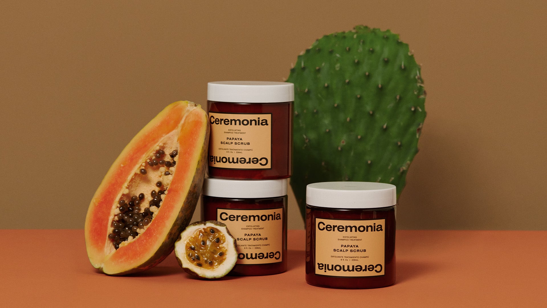 Ceremonia’s papaya scalp scrub with the natural ingredients inside the product pictured around it.