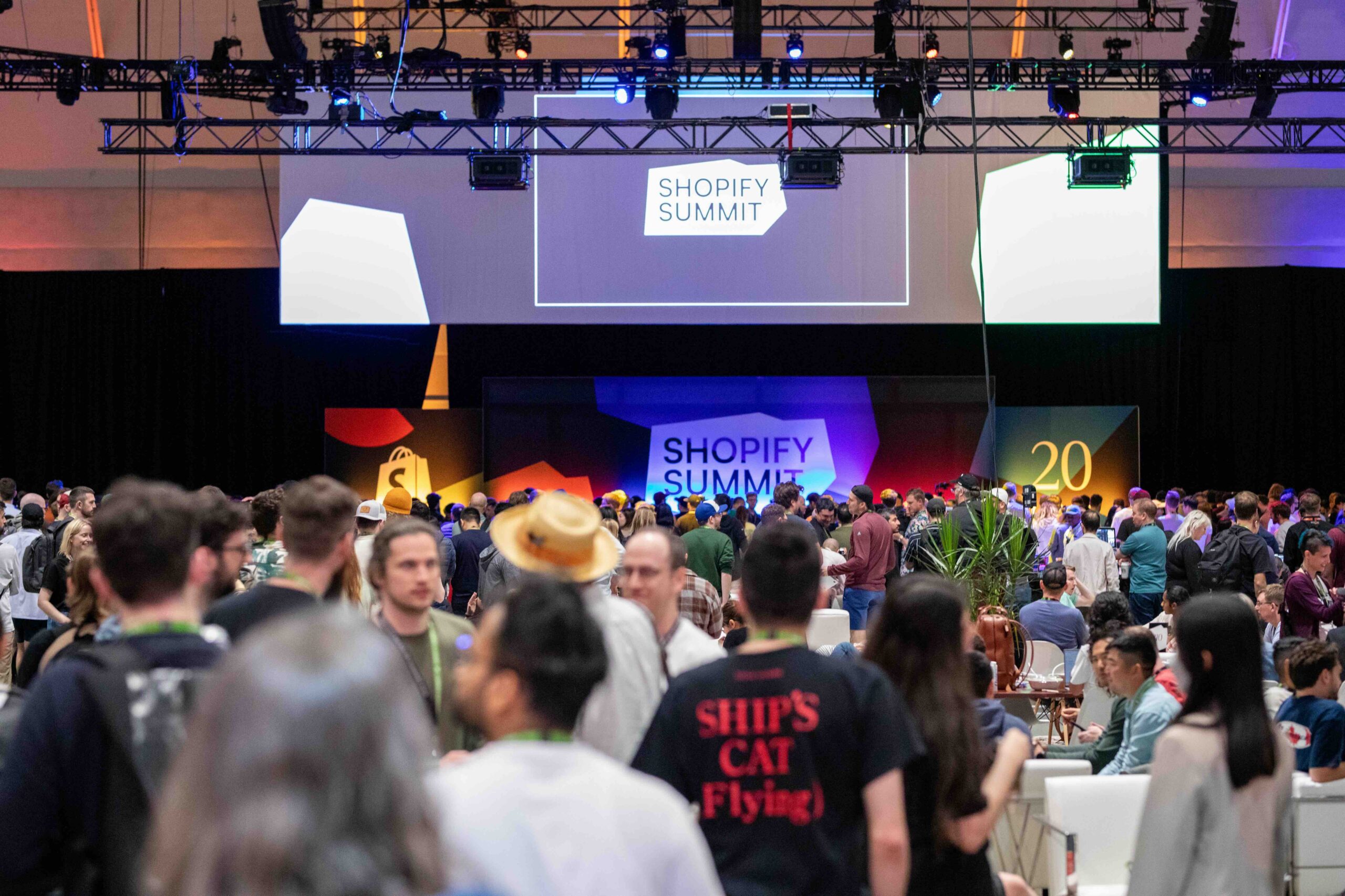 People and signs with Shopify’s logo and “Shopify Summit” celebrating its 20th anniversary.