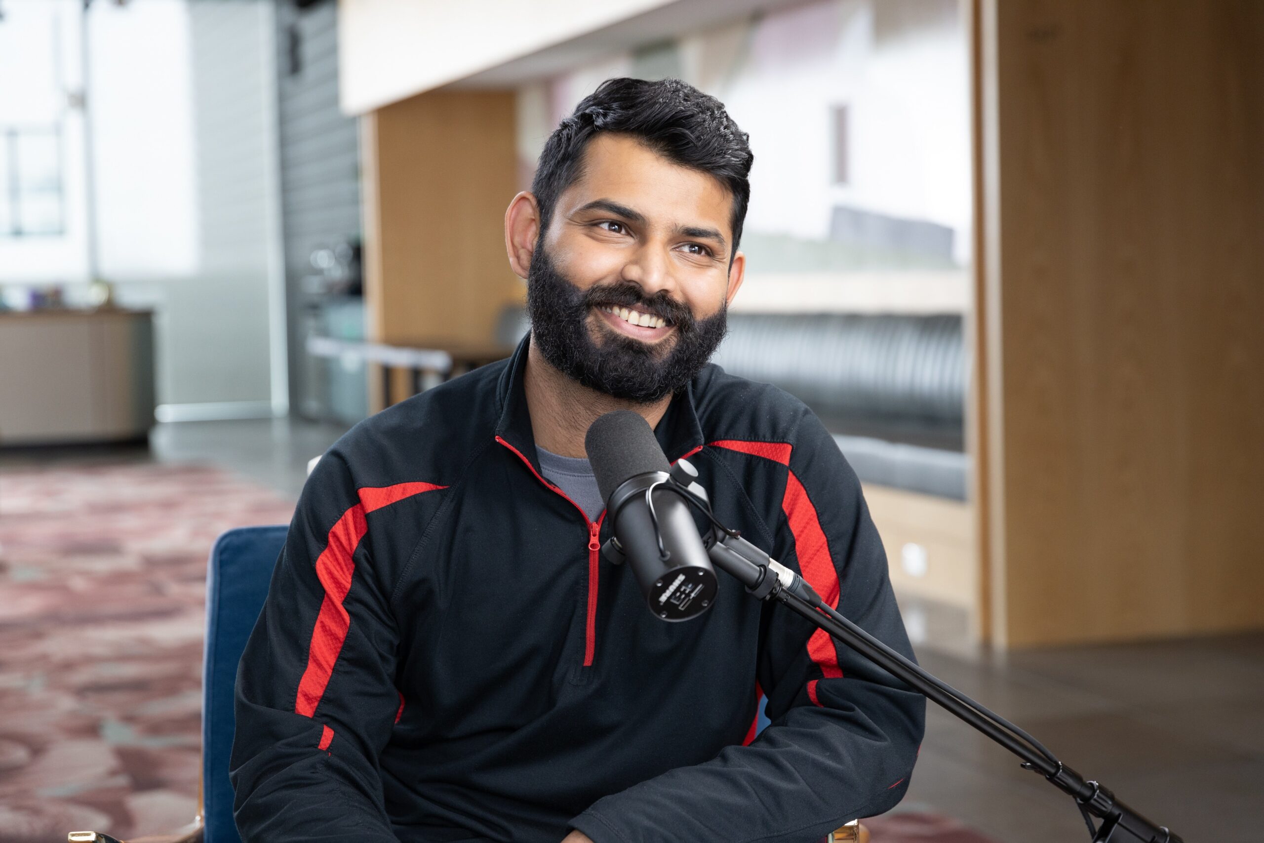 Divy Ohja on the Shopify Masters podcast, smiling and looking up to his left.