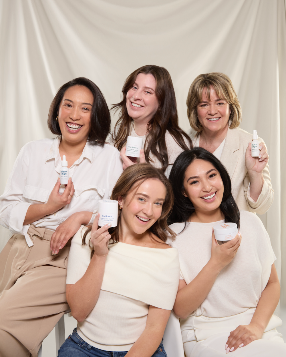 Models smiling and holding Three Ships products against a white backdrop.
