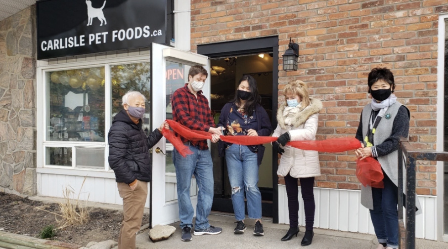 Carlisle Pet Foods ribbon-cutting with owners and local community members outside the storefront.