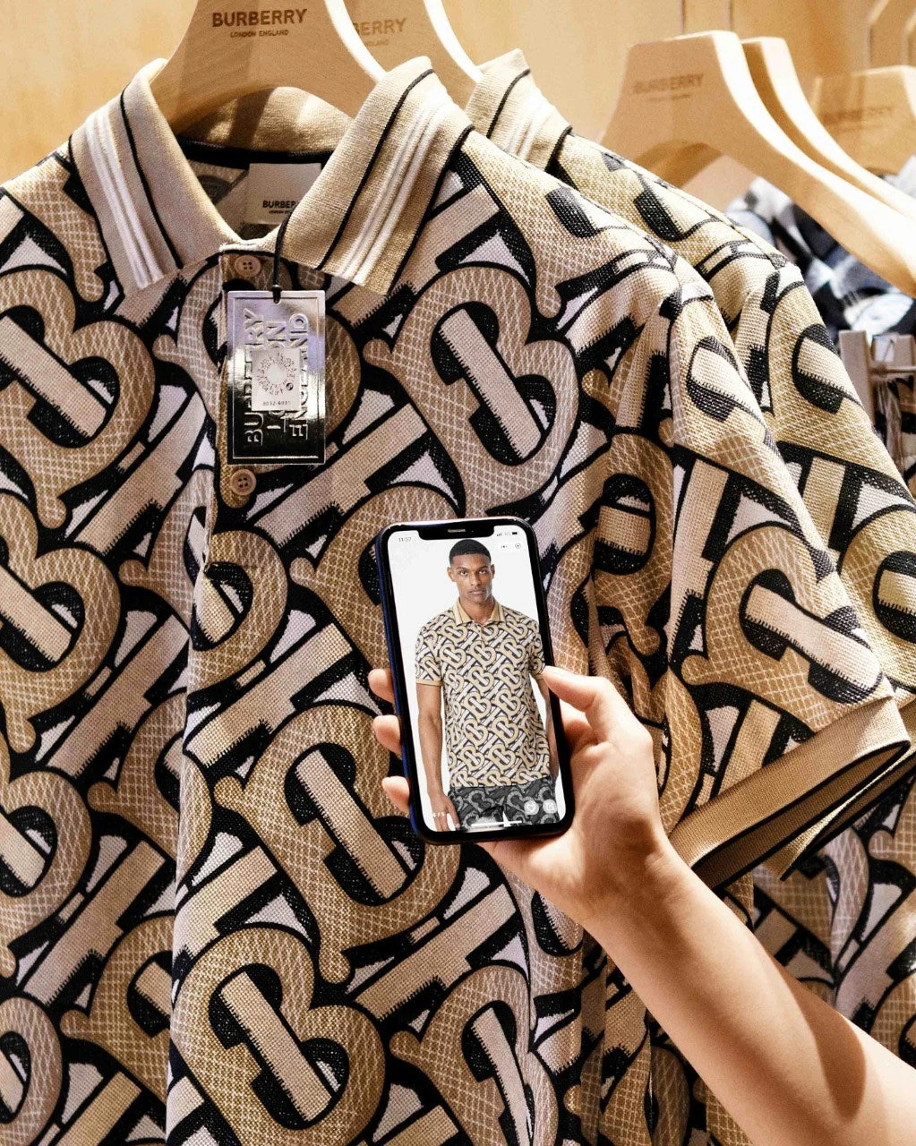 Burberry polo with monogram print shown alongside AR try-on image on a smartphone screen.