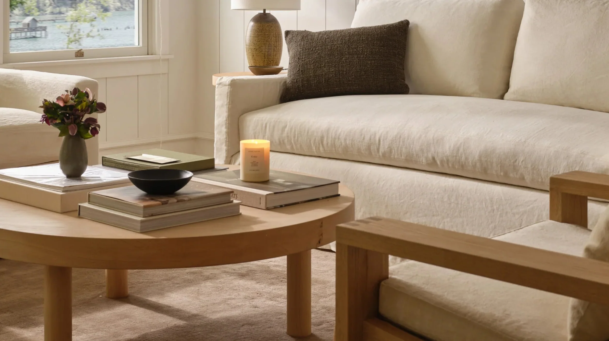 Neutral-toned living room with Jenni Kayne furniture, candle, and coffee table books.